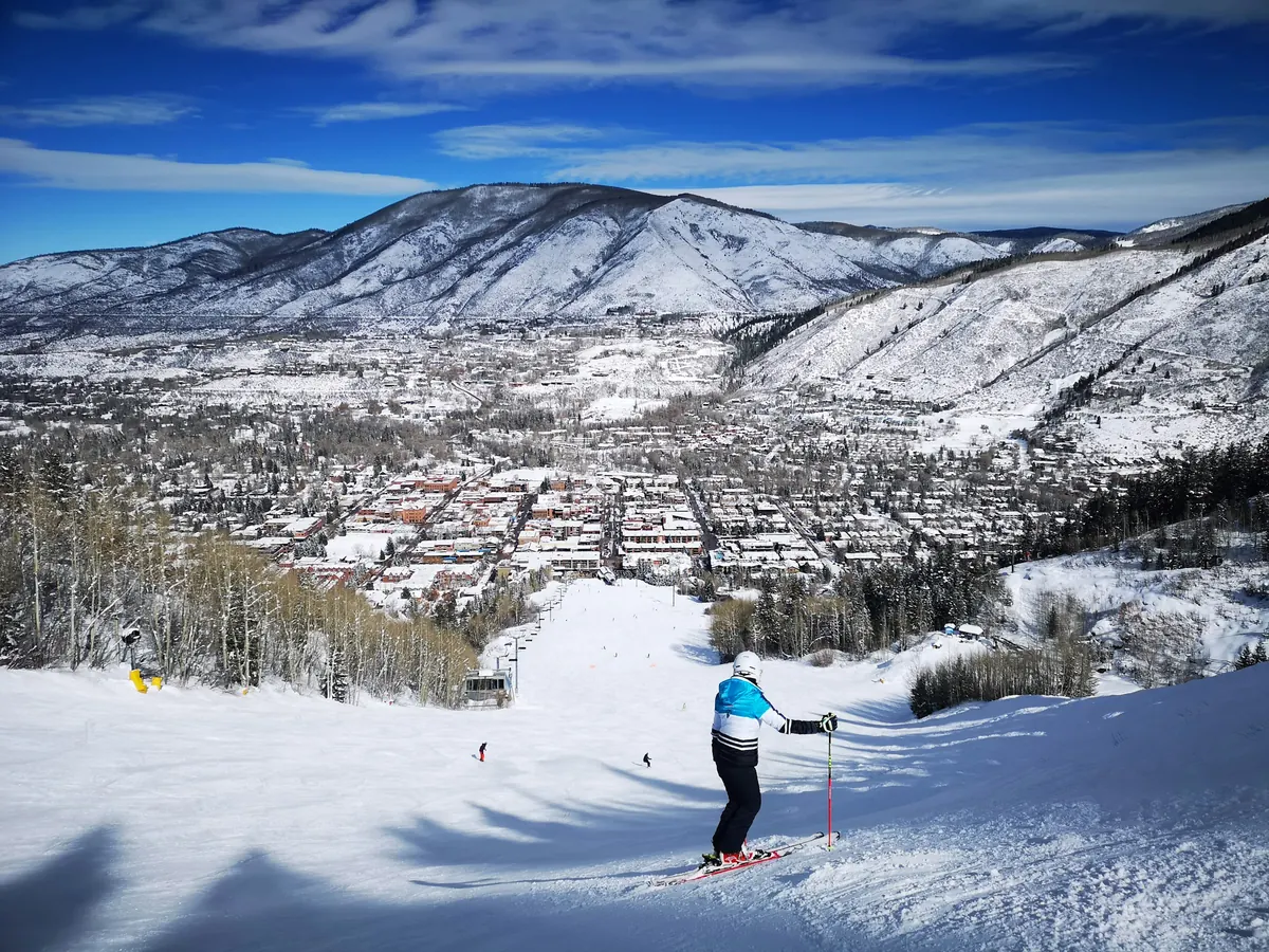 Skier above a snowy mountain town in the Rockies